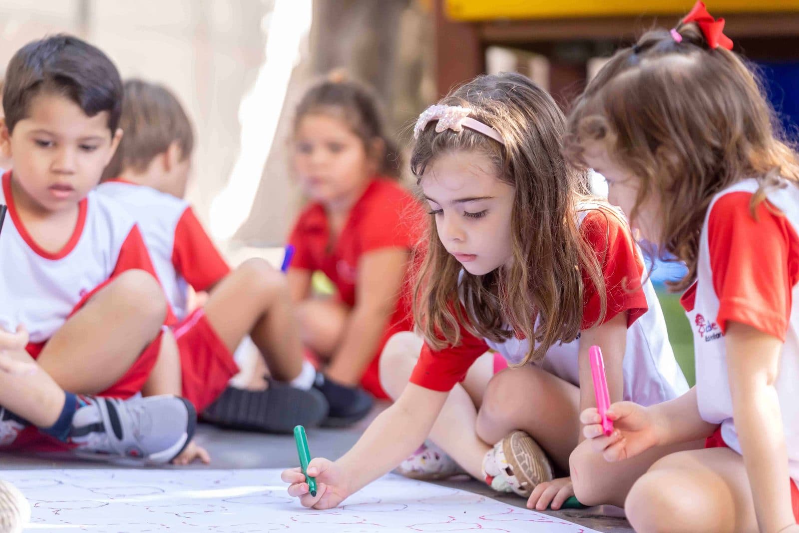 Crianças desenhando juntas em uma folha grande no chão