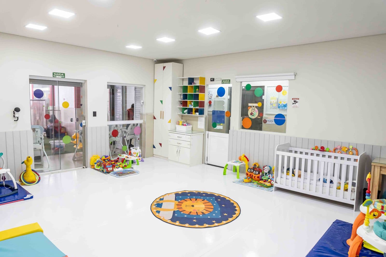 Sala com berço, prateleiras de brinquedos e tapete no chão