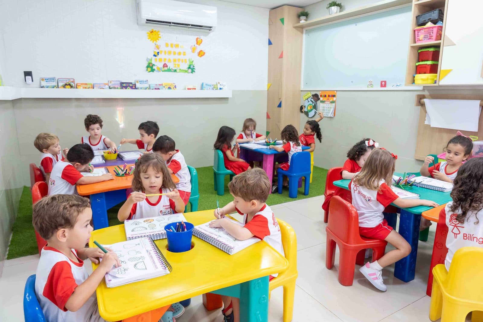 Turma em atividade nas mesinhas coloridas da sala de aula